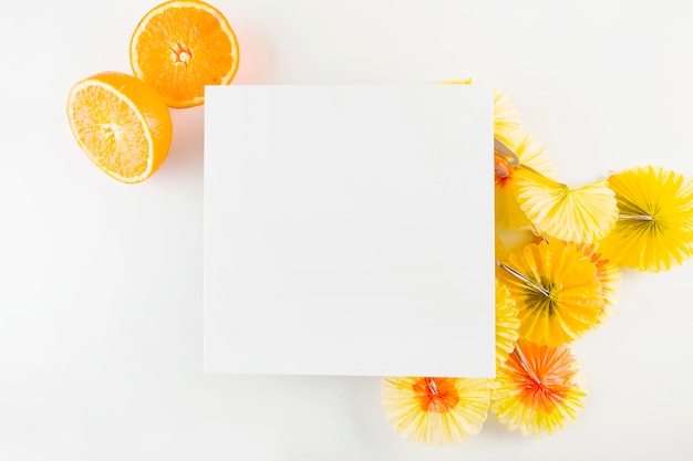 Бесплатное фото Апельсины и коктейльные зонтики возле бумажного листа