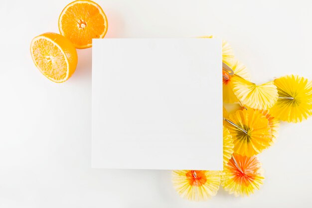 Oranges and cocktail umbrellas near paper sheet