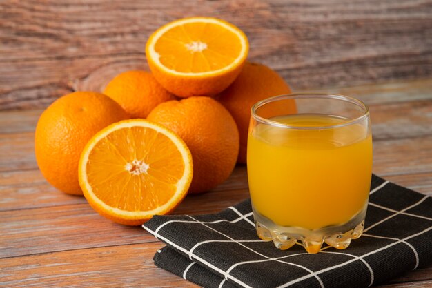Oranges and a glass of juice on a black kitchen towel