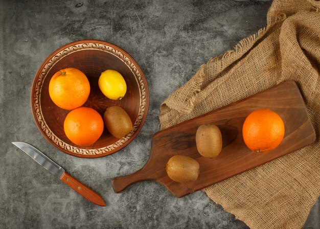 Oranges and kiwies in a bowl and on the cutting board.