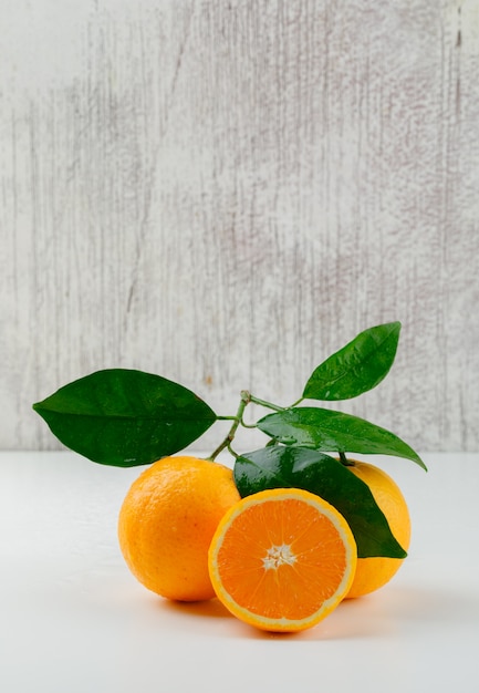 Oranges and slice with branch, side view.