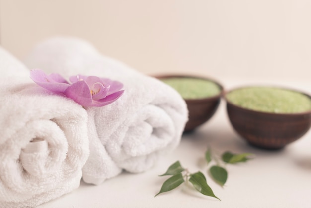 Orchid on rolled up towel with spa salt on white background