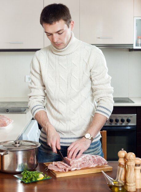 Ordinary guy  cutting meat  at kitchen