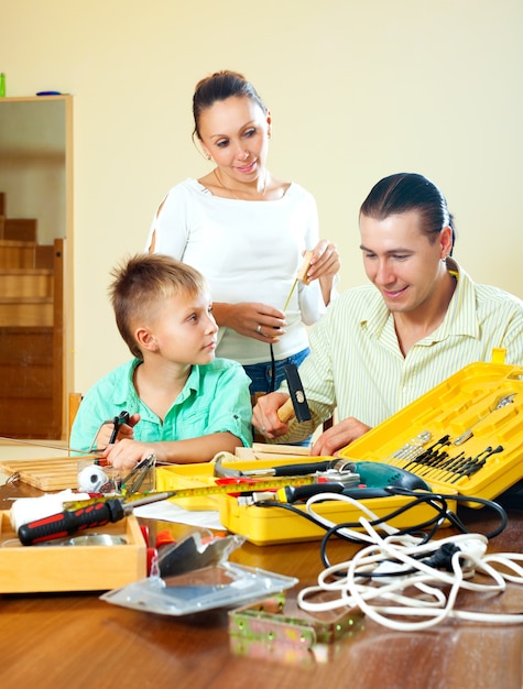 Ordinary nice family of three making something with the working tools