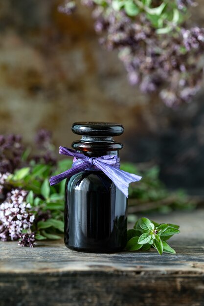 Oregano essential oil in glass bottle on wooden background. copy space