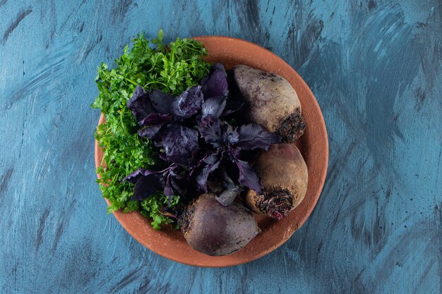 Organic beetroots, dill and basil leaves on ceramic plate. 