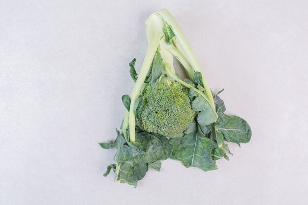 Organic broccoli with leaves on white surface