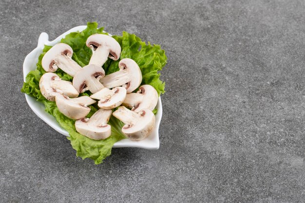 Бесплатное фото Органические нарезанные шампиньоны с салатом на белой тарелке.
