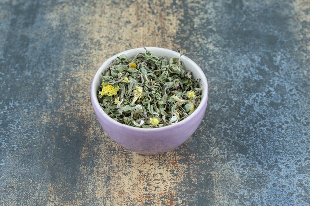 紫色のボウルに有機乾燥茶の葉。