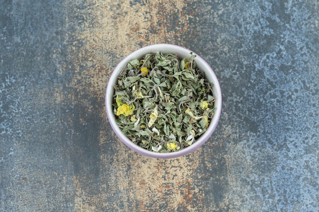 Organic dried tea leaves in white bowl.