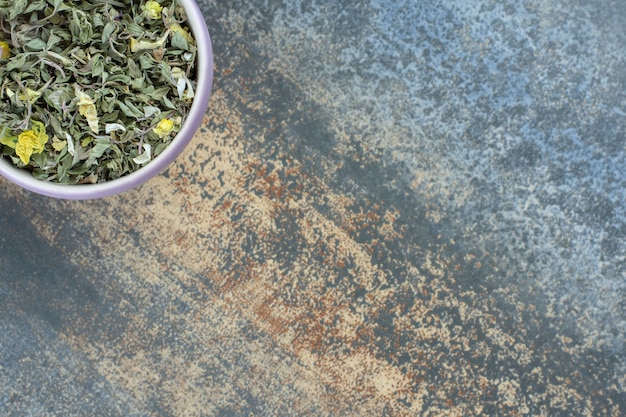 Organic dried tea leaves in white bowl.