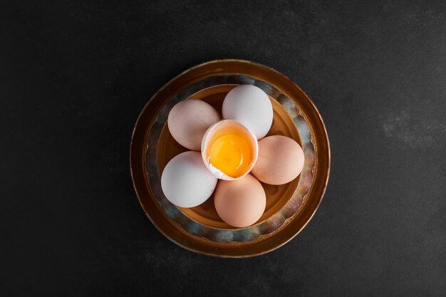 Organic eggs and eggshells in a pottery bowl, top view. 