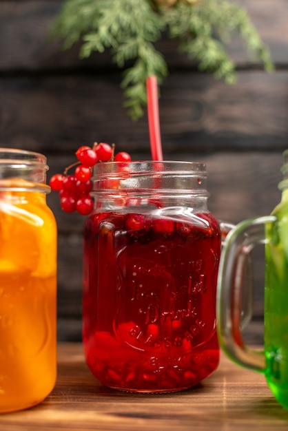 Organic fresh juices in bottles served with tubes and fruits on a brown wooden background