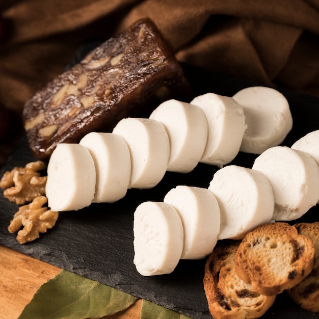 Organic goat cheese, brown cheese, walnut and bread with bay leaves on slate stone