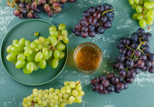 Free photo organic grapes with drink in a tray on plaster background, top view.