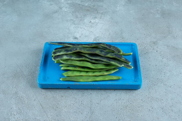 Organic green beans on blue plate.