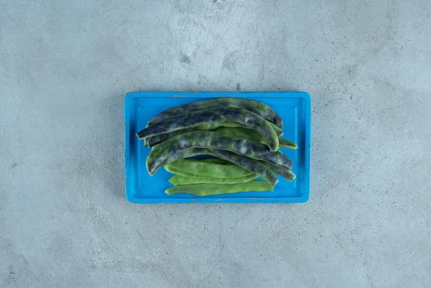 Free photo organic green beans on blue plate.