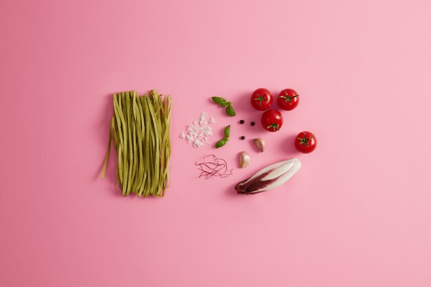 Органическая паста тренетте с зеленым шпинатом с ингредиентами и специями для приготовления вкусной итальянской кухни. Сбор сырых продуктов. В блюдо можно добавить помидоры, чеснок, нити чили, салат из цикория, морскую соль.