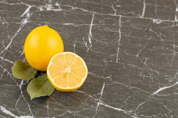 Бесплатное фото Органические половинки и целые лимоны на сером камне.