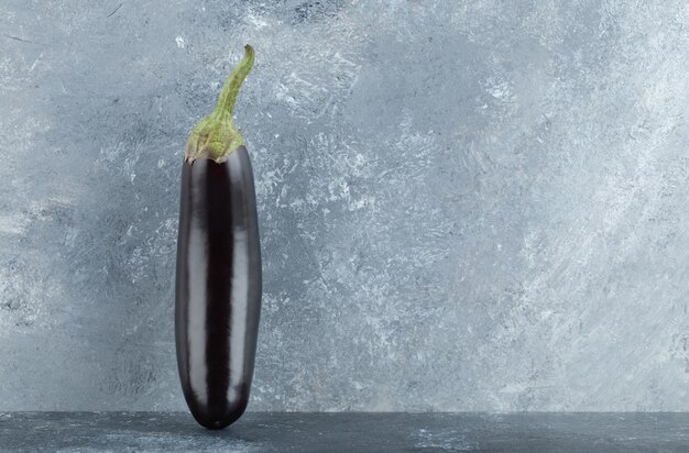 Organic purple eggplants on grey background.