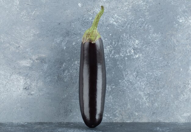 Organic purple eggplants on grey background.