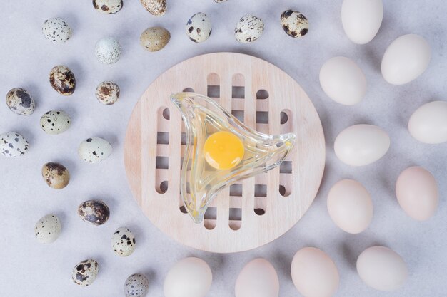 Органические перепелиные яйца и куриные яйца на белой поверхности с яичным желтком.