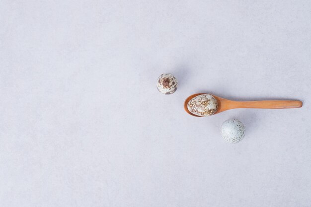 Organic quail eggs on white surface with spoon.