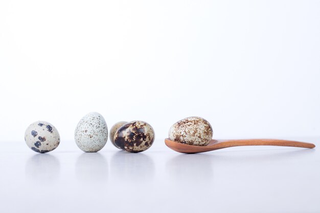Organic quail eggs on white surface with spoon.