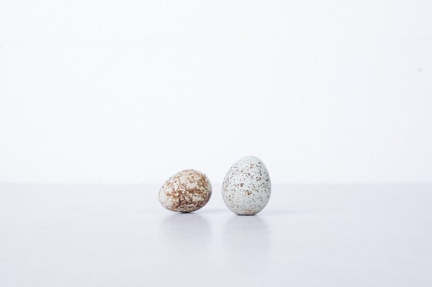 Organic quail eggs on white surface.