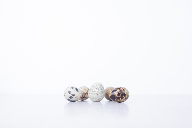 Organic quail eggs on white surface.