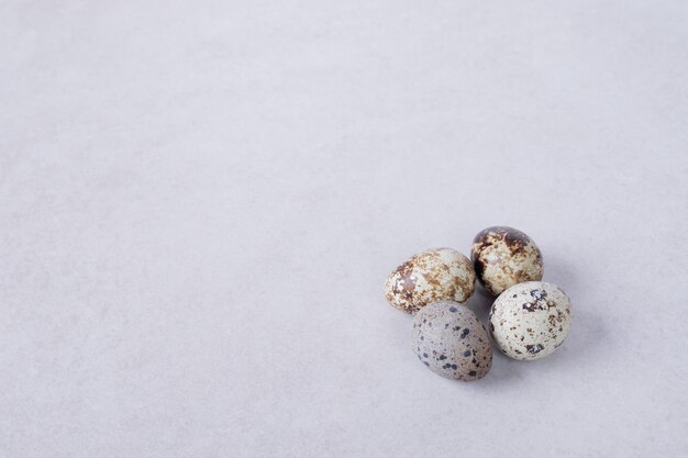 Organic quail eggs on white surface.