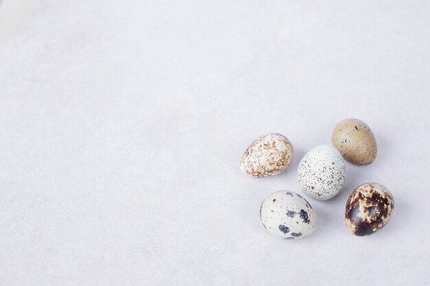 Organic quail eggs on white surface.