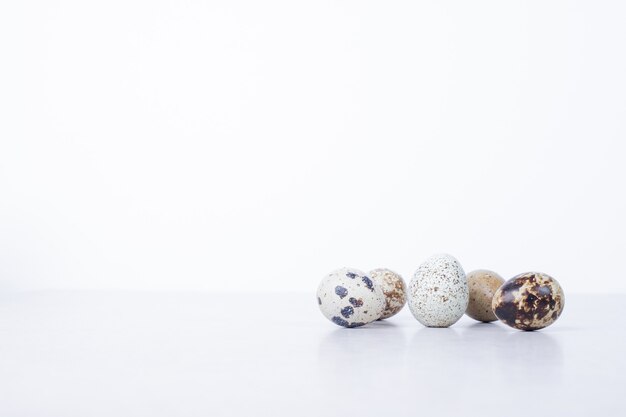 Organic quail eggs on white surface.