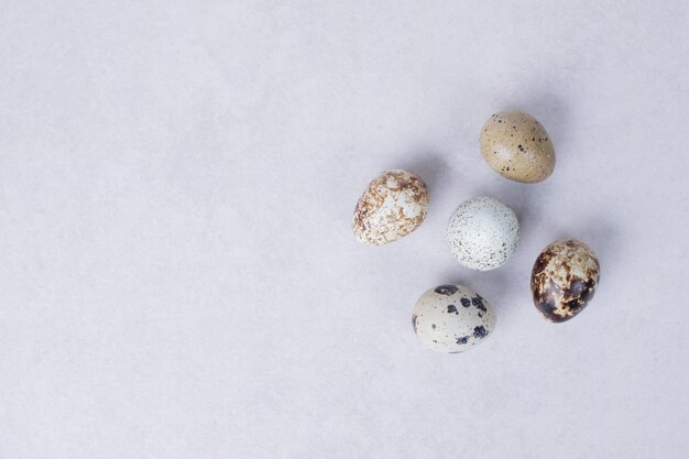 Organic quail eggs on white surface.