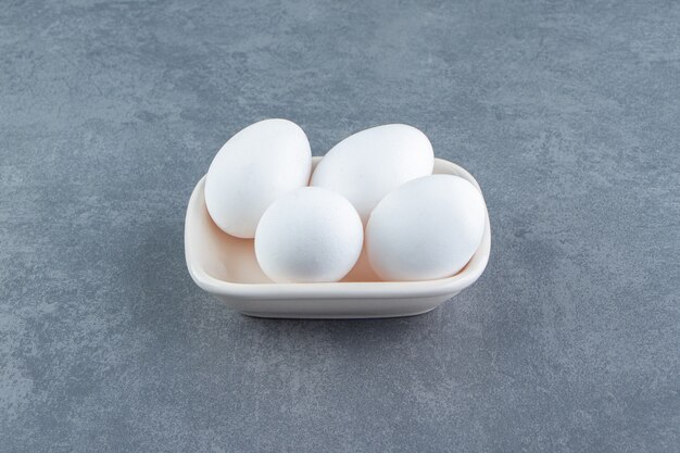Органические сырые яйца в белой миске.