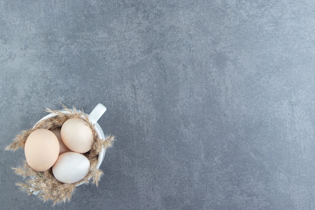 Organic raw eggs in white mug.