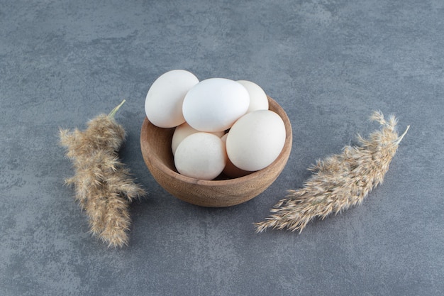 Foto gratuita uova crude organiche in ciotola di legno.