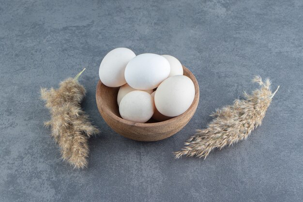 Organic raw eggs in wooden bowl.
