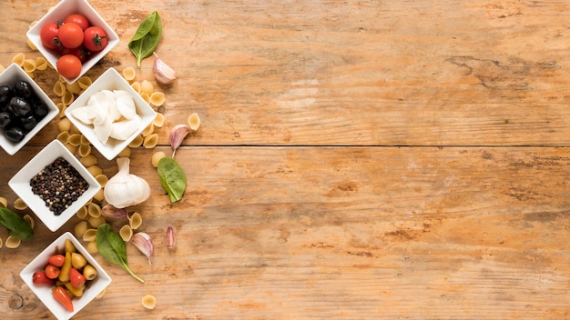 Organic raw ingredients with conchiglie pasta on brown desk