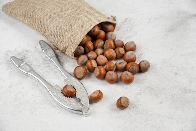 Organic shelled hazelnuts in burlap with nut cracking tool. 