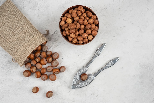 Organic shelled and kernels of hazelnuts in burlap with cracking tool. 