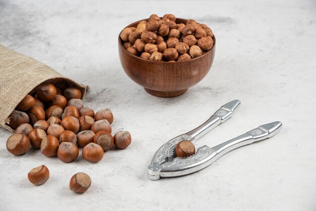 Organic shelled and kernels of hazelnuts in burlap with cracking tool. 