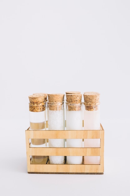 Organic spa product test tubes arranged in wooden container on white surface
