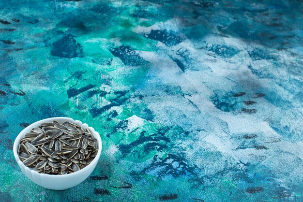 Organic sunflower seed in a bowl on the blue surface