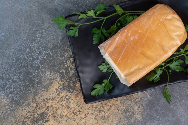 Organic yellow cheese on black plate with coriander.