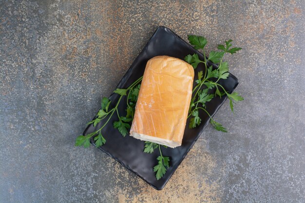 Free photo organic yellow cheese on black plate with coriander