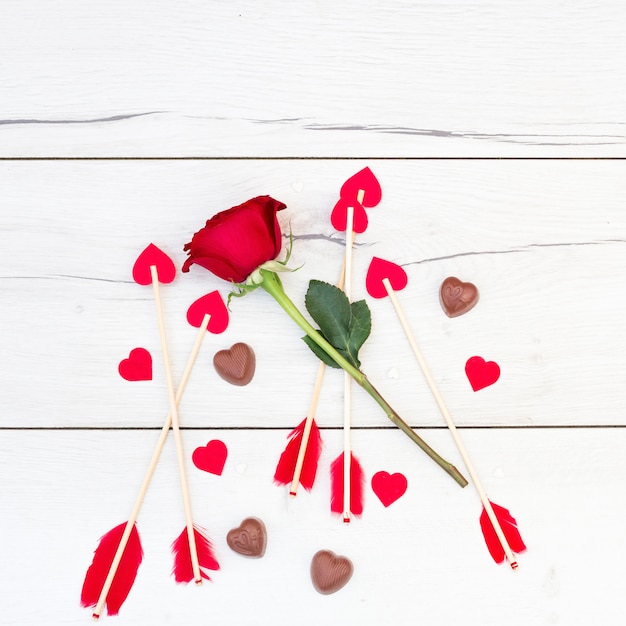 Ornament feathers on wands with little hearts near flower and candies 