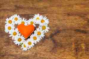 Free photo ornamental heart of white flowers and orange toy