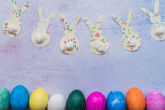 Ornamental paper rabbits on twist near Easter eggs