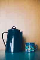 Free photo ornamental porcelain teapot and mug against wooden backdrop